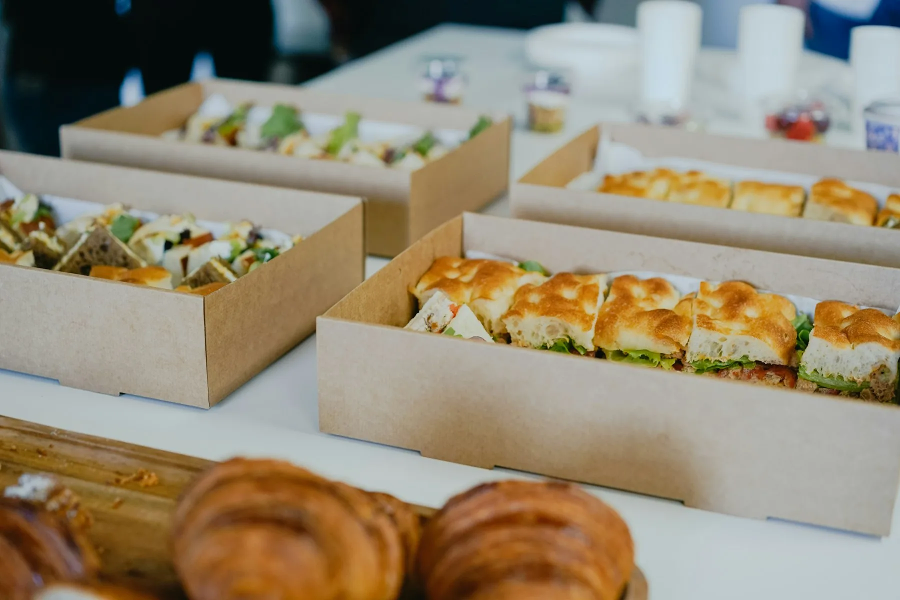 Boîtes de sandwichs et de viennoiseries posées sur une table de réunion